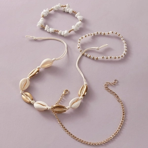 Flat lay of bohemian shell necklace and beaded anklet set in gold and white tones