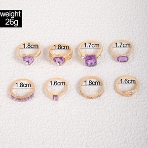 Detailed view of 8-piece gold ring set with purple gemstones and size measurements
