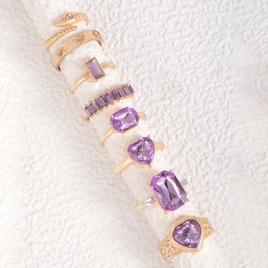 Macro detail of eight-piece gold ring set with purple heart and snake stones