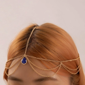 Close-up of golden multi-layer head chain with a teardrop blue gem pendant decoration