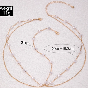 Detailed view of layered gold chain body jewelry with white pearls and size markers