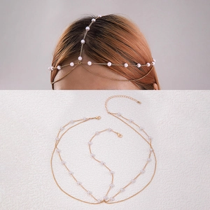 Detail of bohemian gold chain headpiece with white pearls on a textured background