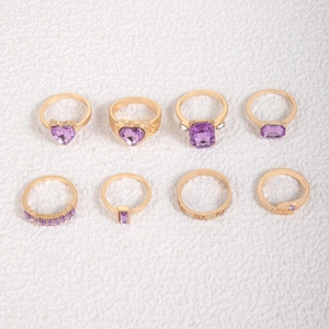 Macro view of 8-piece gold-tone ring set featuring purple gemstones and snake designs