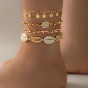 Detail of four-piece layered beach anklet set with natural shells and gold chain