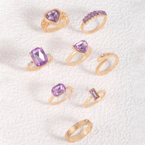 8pcs gold heart and snake ring set with purple gemstones on white background
