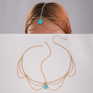 Detail of bohemian gold head chain with layered metal links and turquoise stone drop