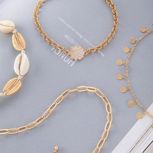 Flat lay of beach style layered seashell bracelets and gold chain jewelry set for summer