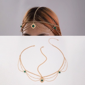 Detail view of gold layered head chain with green stones in bohemian style on white background