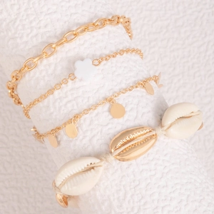 Macro detail of bohemian shell bracelet set with gold chains and natural white shells