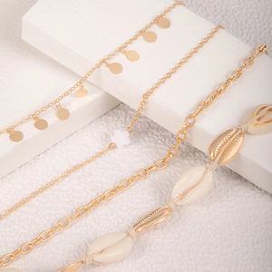 Detail of beach style anklet set featuring natural shells and gold flower charms