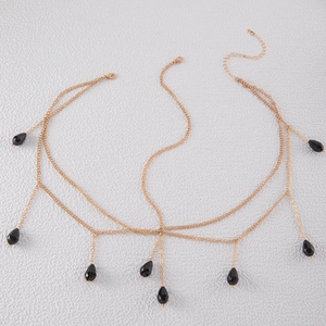 Macro detail of multi-layer gold chain headpiece with black teardrop beads and lobster clasp