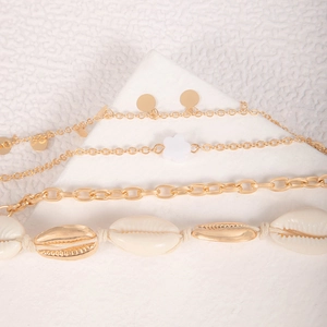 Detail of multi-layered beach anklet set featuring natural shells and gold-tone chains