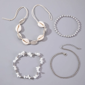 Detailed set of beach-style shell, pearl, and turquoise stone layered anklets on grey