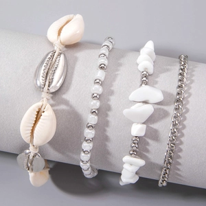 Detail view of bohemian shell anklets set with natural cowrie and silver metallic charms