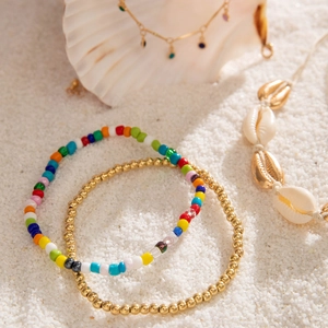 Detail of bohemian beach jewelry set with sea shells and colorful beads on white sand