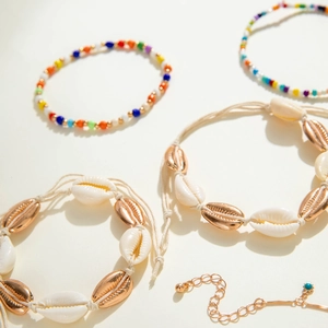 Close-up of bohemian shell anklets with colorful beads and rose gold shell weave