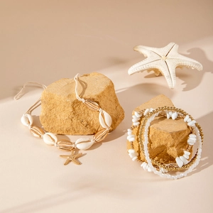 Close-up of bohemian shell pendant necklace and beaded bracelets on natural stone base