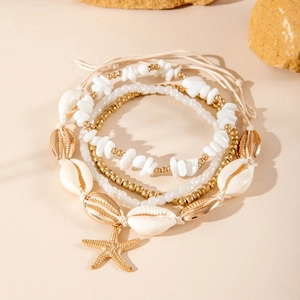 Detail of beach-style layered anklet with natural sea shells and golden starfish pendant
