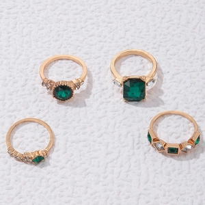 Detailansicht eines vierteiligen Goldring-Sets mit smaragdgrünen Steinen und Zirkonia