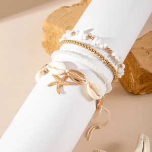 Detail of beach-style multilayer anklets with natural shells, starfish, and golden beads