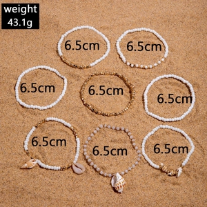Detailed view of bohemian shell beaded bracelets set on sandy beach background