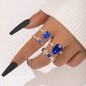 Ensemble de 4 bagues dorées avec saphirs bleus et zircons clairs portées par un mannequin