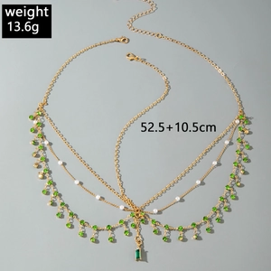 Detail view of a gold bohemian head chain with green gems and white pearls, 13.6g weight