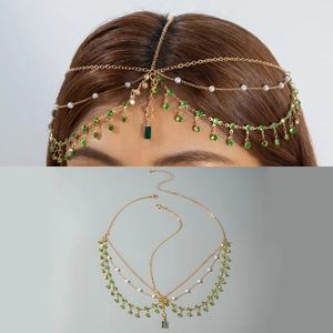 Detail of bohemian gold head chain featuring green crystals and white faux pearls