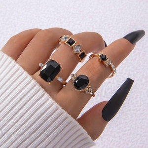 Nahaufnahme eines vierteiligen Goldring-Sets mit schwarzen Edelsteinen und Kristallen