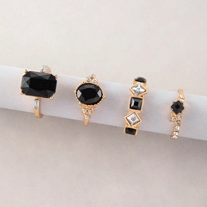 Makroansicht des 4-teiligen goldenen Ring-Sets mit schwarzen Edelsteinen und Kristallen