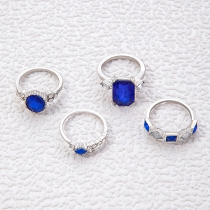 Detail von vier silberfarbenen Ringen mit blauen Edelsteinen und weißen Zirkonia-Akzenten