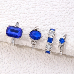 Detailsicht von vier Silberringen mit blauen Kristallen auf weißen Displaysäulen