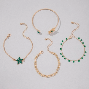 Détail d'un ensemble de quatre bracelets dorés avec gemmes vertes et motifs de fleurs solaires