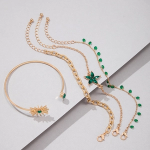 Vue détaillée de 4 bracelets superposés dorés avec des gemmes vertes et breloques fleurs