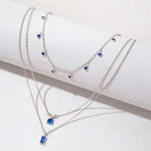 Vue détaillée d'un collier triple rang avec pierre bleue rectangulaire et chaînes argentées