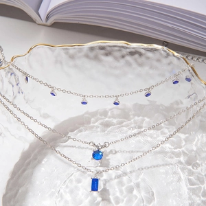 Gros plan sur collier triple rang argenté avec pendentifs géométriques en pierres bleues