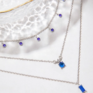 Vue détaillée du collier argenté à plusieurs rangs avec pierres précieuses bleues