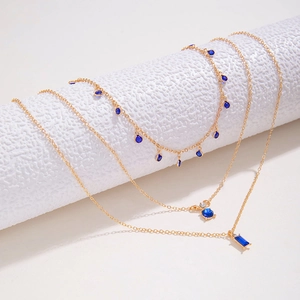 Détail d'un collier triple épaisseur en or avec pierres précieuses bleues et cristaux