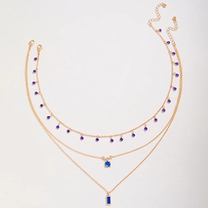 Détail d'un collier doré à trois rangs avec cristaux bleus et fermoir mousqueton