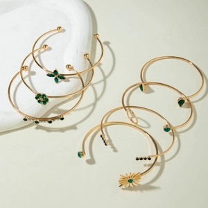 Détail d'un ensemble de six bracelets dorés avec pierres vert émeraude sur pierre