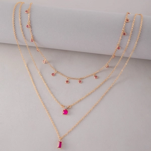 Détail de collier doré à plusieurs rangs avec pendentifs rubis ronds et rectangulaires