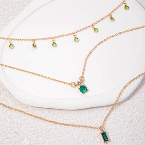 Détail macro du collier triple rang doré avec pendentifs en pierres vertes et cristaux