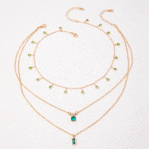 Vue détaillée du collier triple rang doré orné de pendentifs en cristal vert émeraude