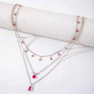 Détail d'un collier triple rang argenté avec des pendentifs en cristal rose géométrique