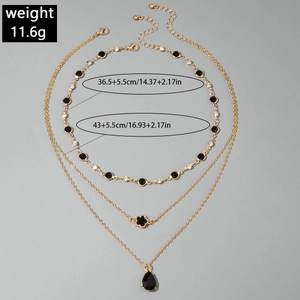 Détail macro du collier triple rang doré avec des pierres noires et pendentifs gouttes