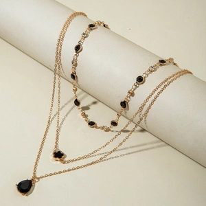 Détail d'un collier doré triple rang avec pendentif goutte noire et trèfle