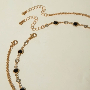 Détail du collier multicouche doré avec cristaux noirs et transparents et fermoir mousqueton