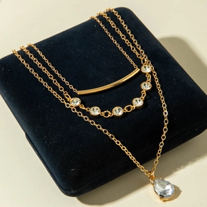 Détail d'un collier doré à trois rangs avec pendentifs en cristal sur un écrin à bijoux