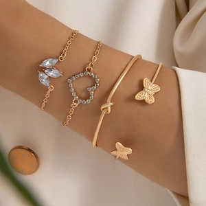 Close-up of gold-plated bracelet set featuring butterfly motifs, heart charms, and crystal leaves