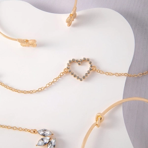 Detail of gold-tone jewelry set with heart, leaf, and butterfly motif bracelets
